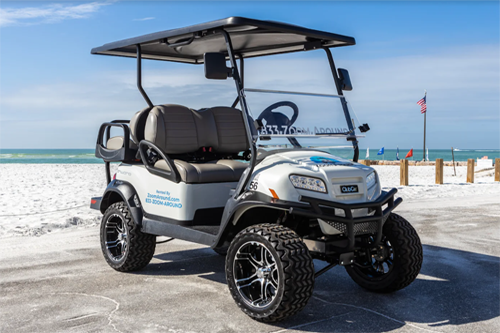 A white golf cart parked on the beach.
