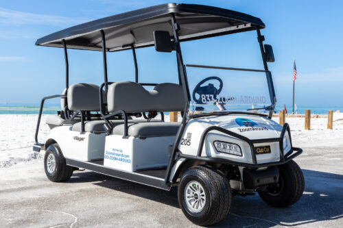 A white and black golf cart parked on the beach.
