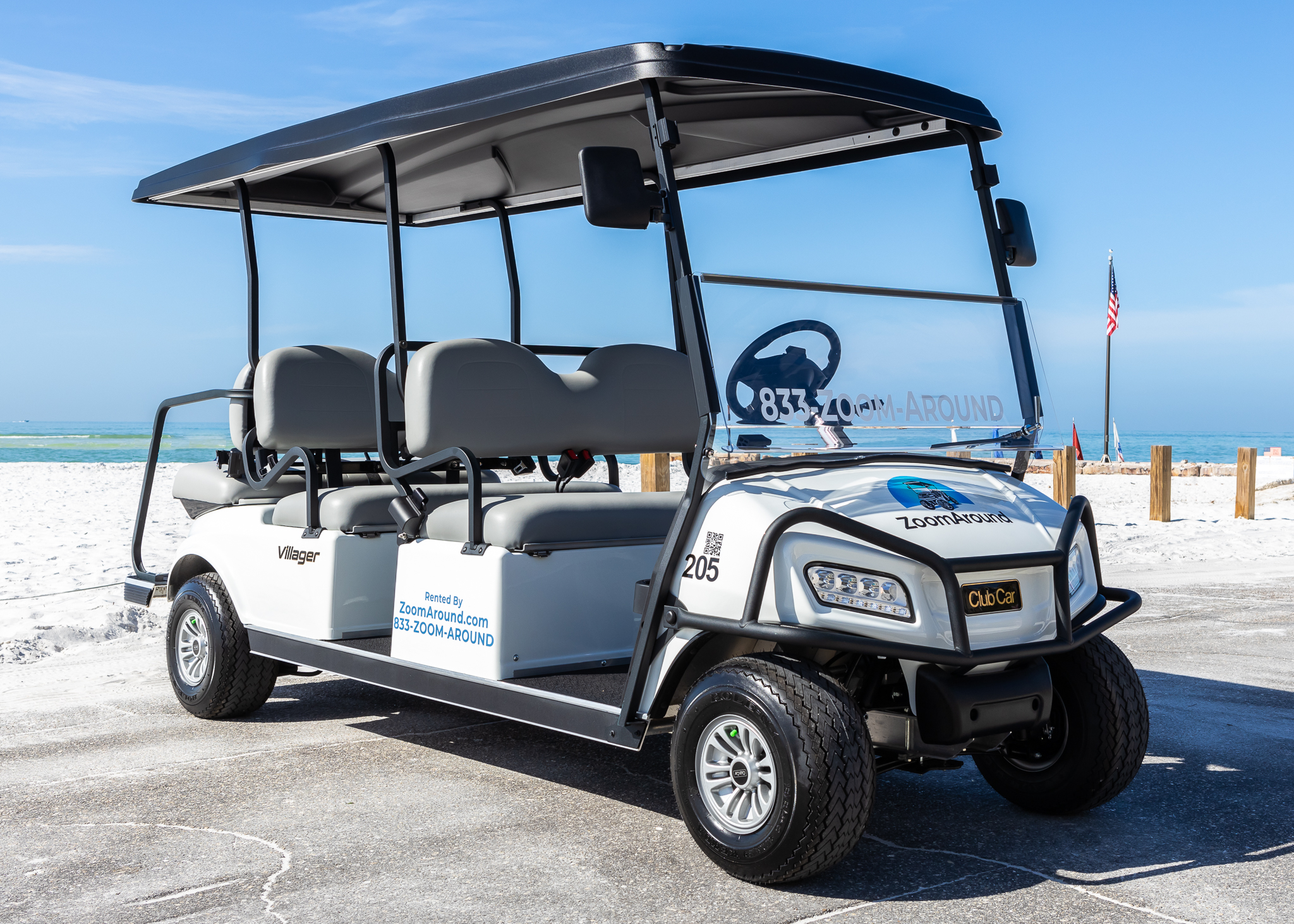 A white and black golf cart parked on the beach.
